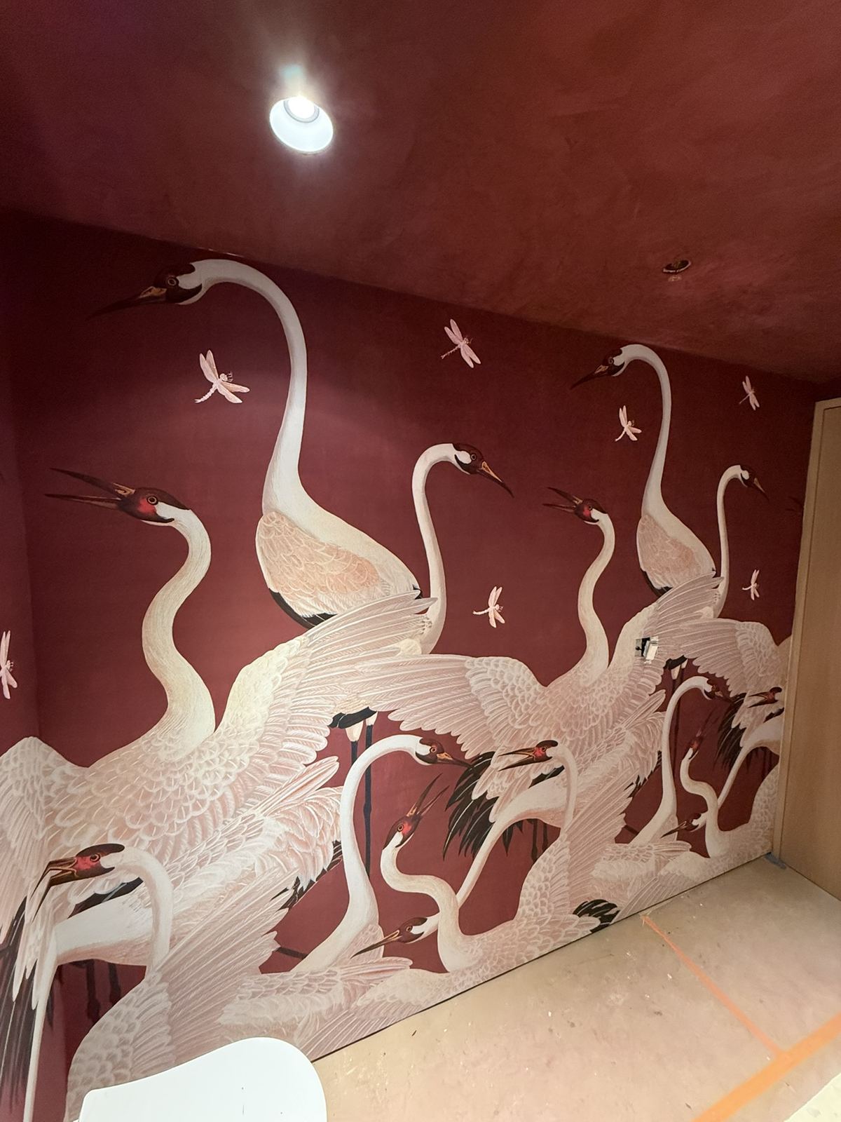 The same powder room with a burgundy crane mural installed